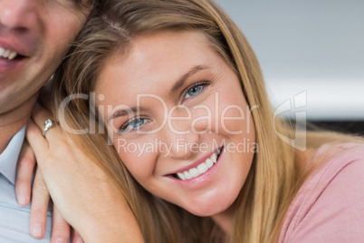 Happy couple sitting on the couch smiling at camera focus on wom
