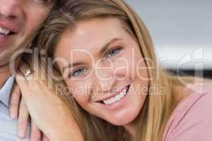 Happy couple sitting on the couch smiling at camera focus on wom