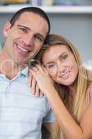 Cute couple sitting on the couch smiling at camera