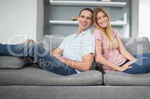 Relaxed couple sitting back to back on the couch together