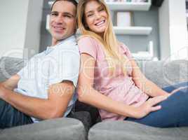 Content couple sitting back to back on the couch together