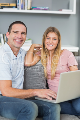 Cheerful couple sitting using laptop on the couch together