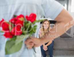 Man hiding bouquet of roses from girlfriend on the couch