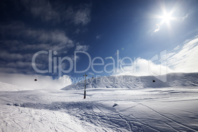 ski slope, gondola lift and blue sky with sun