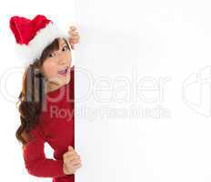Santa girl peeking from behind blank sign billboard.