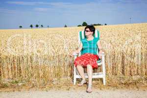 woman sitting in the garden chair in front of the wheat field