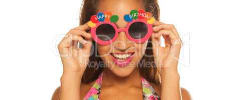 bautiful girl celebrating wearing birthday sunglasses on white