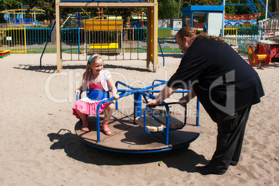dad rolls his daughter on a small carousel