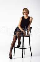 beautiful woman in black dress posing sitting on a chair