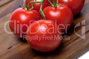 bunch of fresh tomatoes with water drops on wooden cutting board