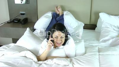 Smiling lady talking via mobile phone and laying on the bed