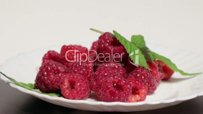 Ripe raspberries on white plate.