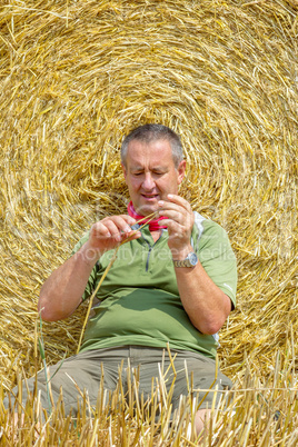 Organic farmer sitting in front of bales of straw