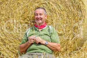 Organic farmer sitting in front of bales of straw