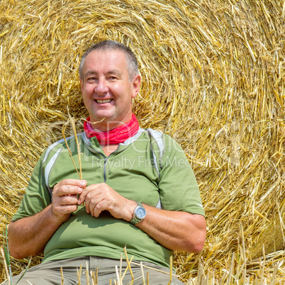 Organic farmer sitting in front of bales of straw