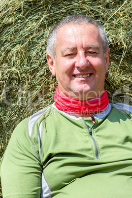 Organic farmer is resting against the hay bales