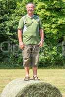 Organic farmer is standing on the hay bales