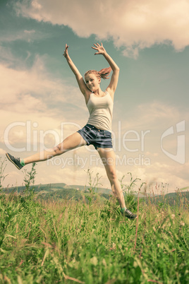 The girl jumps on a green grass