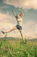 The girl jumps on a green grass