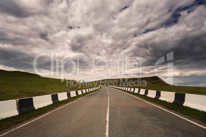 asphalt road to horizon in cloudy sky