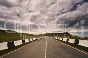 asphalt road to horizon in cloudy sky