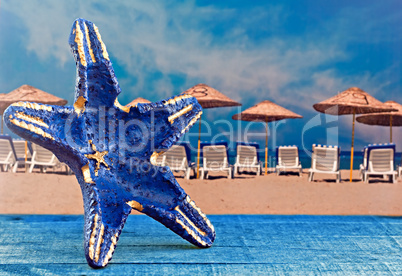 Blue starfish shape against parasols on beach