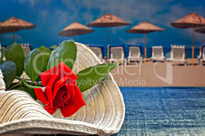 Womans summer hat with red rose with empty beach