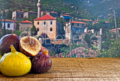 fresh figs on rustic wooden table against village background