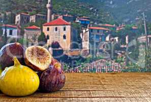 fresh figs on rustic wooden table against village background
