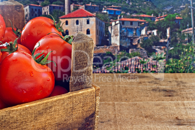 Box of red ripe tomatoes with old countryside background