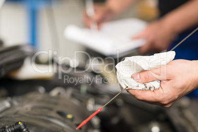 Hand of car mechanic checking oil