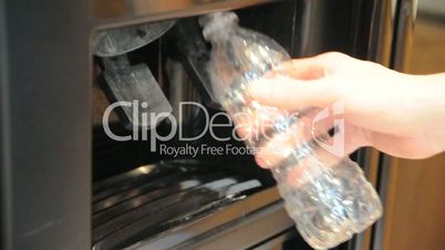 Refilling an empty water bottle from a refrigerator