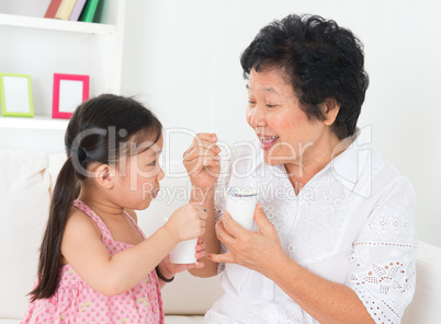 Grandmother and grandchild eating yoghurt