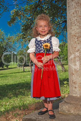 kleines Bayerisches Mädchen im Dirndl mit Sonnenblume