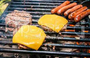 hamburgers with cheese and hot dogs on grille