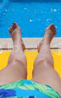 Legs of a woman relaxing poolside