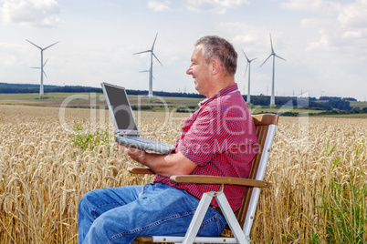 Man with laptop in cornfield