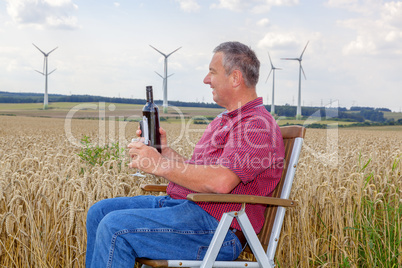 Man sitting with wine bottle in cornfield