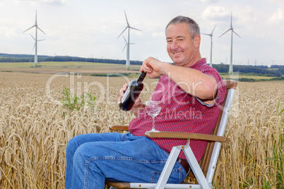 Man sitting with wine bottle in cornfield