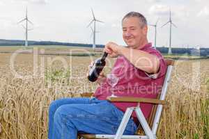 Man sitting with wine bottle in cornfield