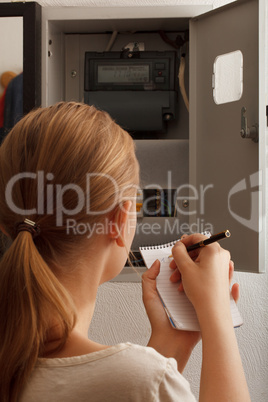 young woman rewrites the electrical meter readings