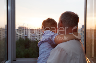 grandfather and grandson embracing on the balcony