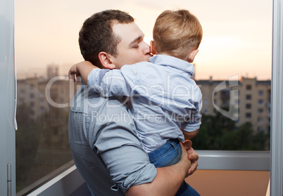father kisses his son on the balcony