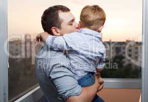father kisses his son on the balcony
