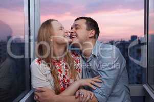 young couple on the balcony embracing and laughing