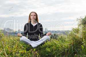 young girl makes yoga exercises outdoors.