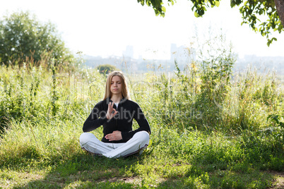young woman practicing yoga in the city park