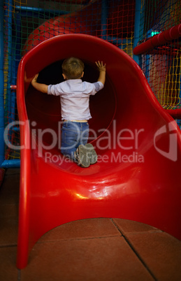 boy is sitting at the slide hole