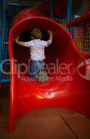boy is sitting at the slide hole