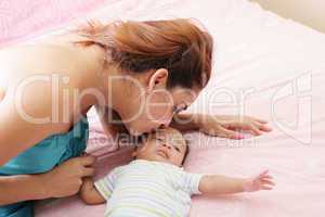 Young mother kissing her small newborn
